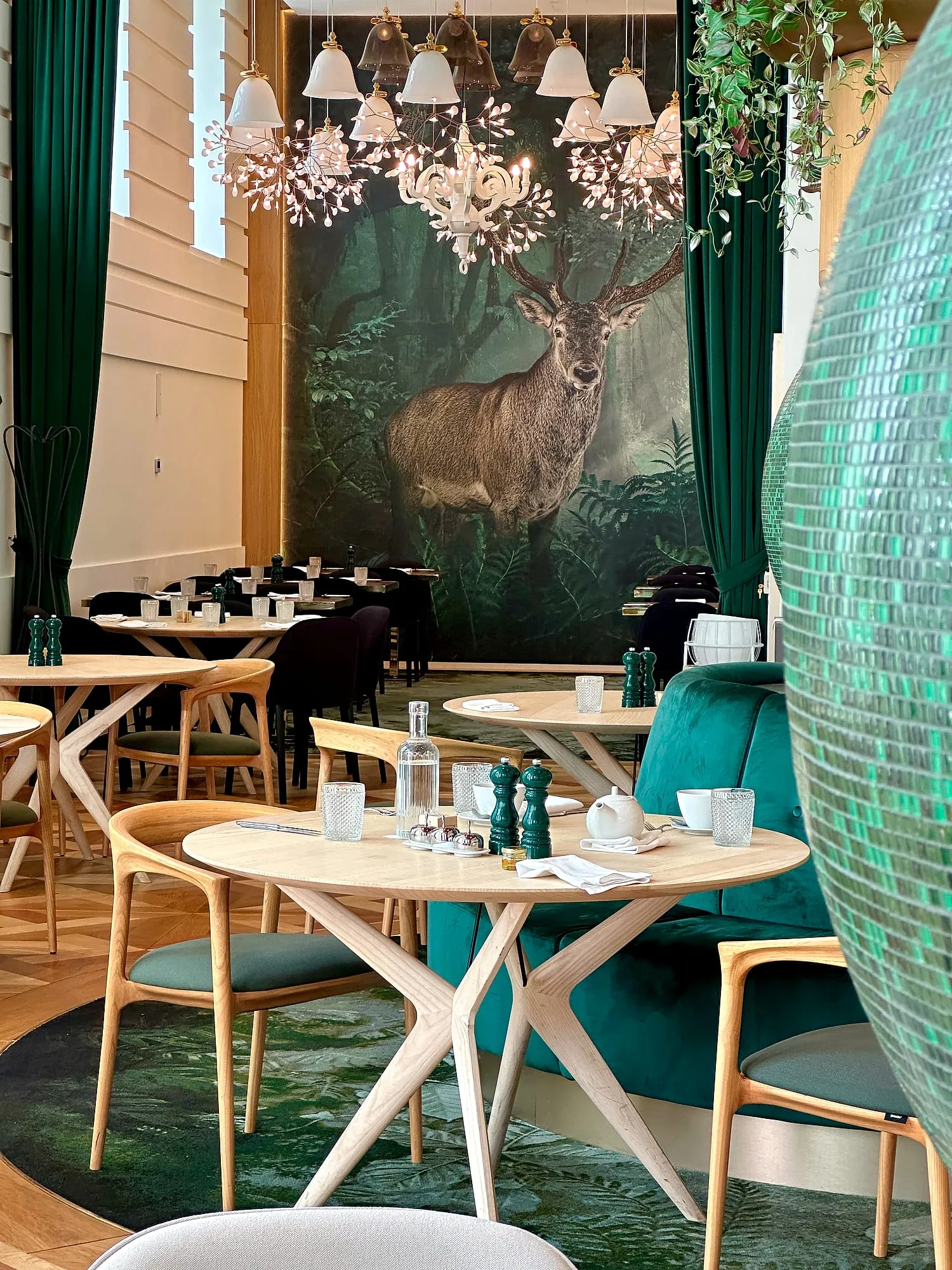 Tables set for breakfast in the green dining room of the Kimpton BEM in Budapest.